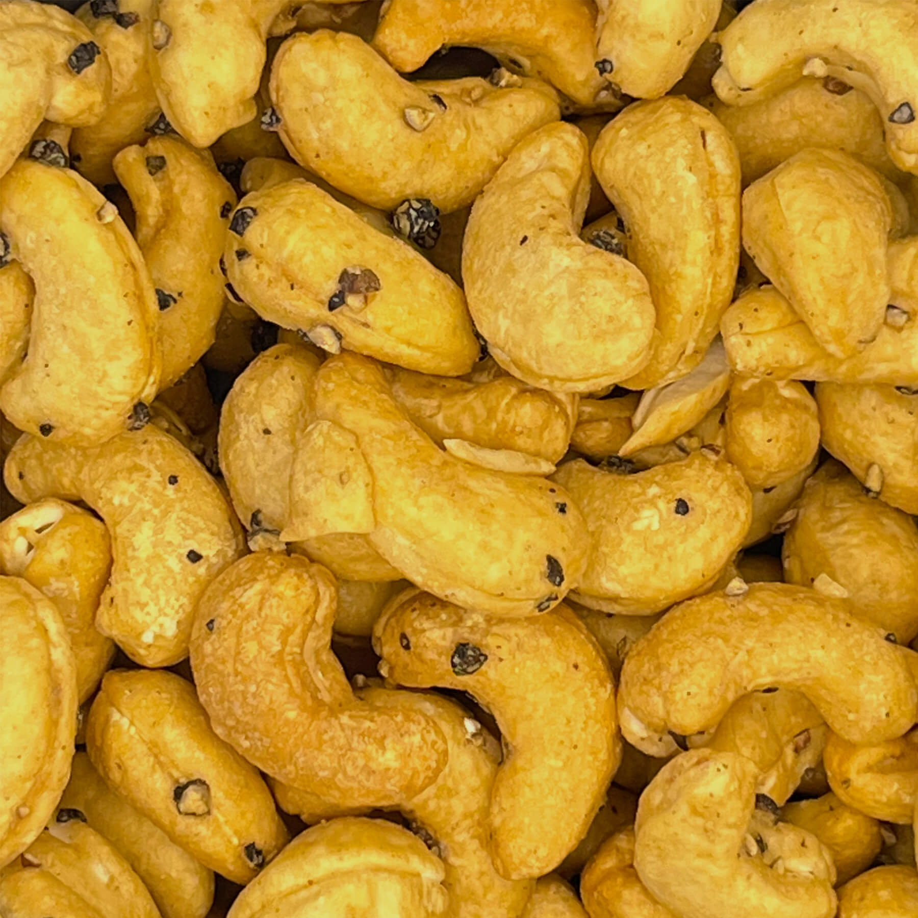 Nahaufnahme gerösteter Cashewkerne mit grob geschrotetem schwarzem Kampot Pfeffer