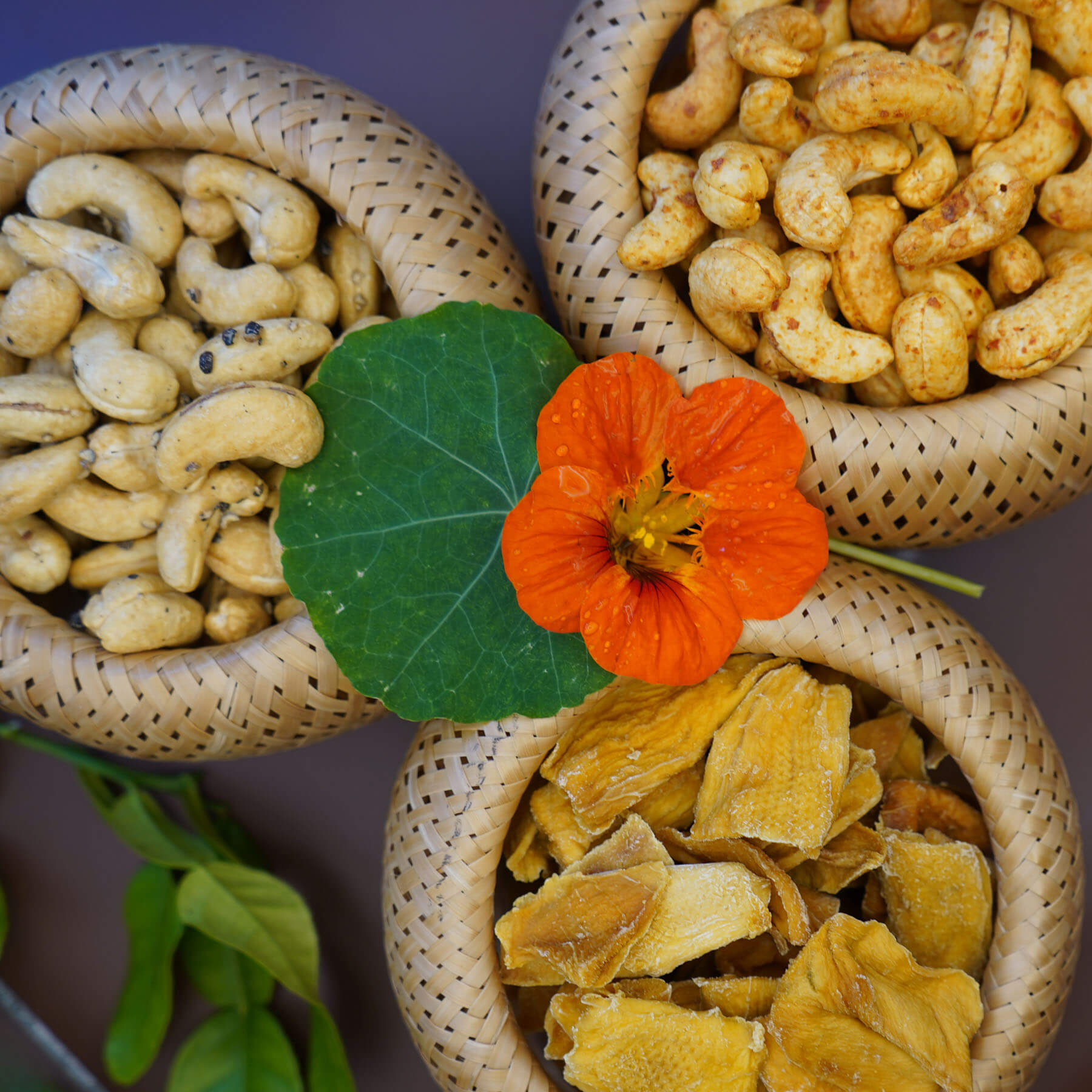 Geröstete Cashews, Pfeffer-Cashews und getrocknete Mango in geflochtenen Schalen
