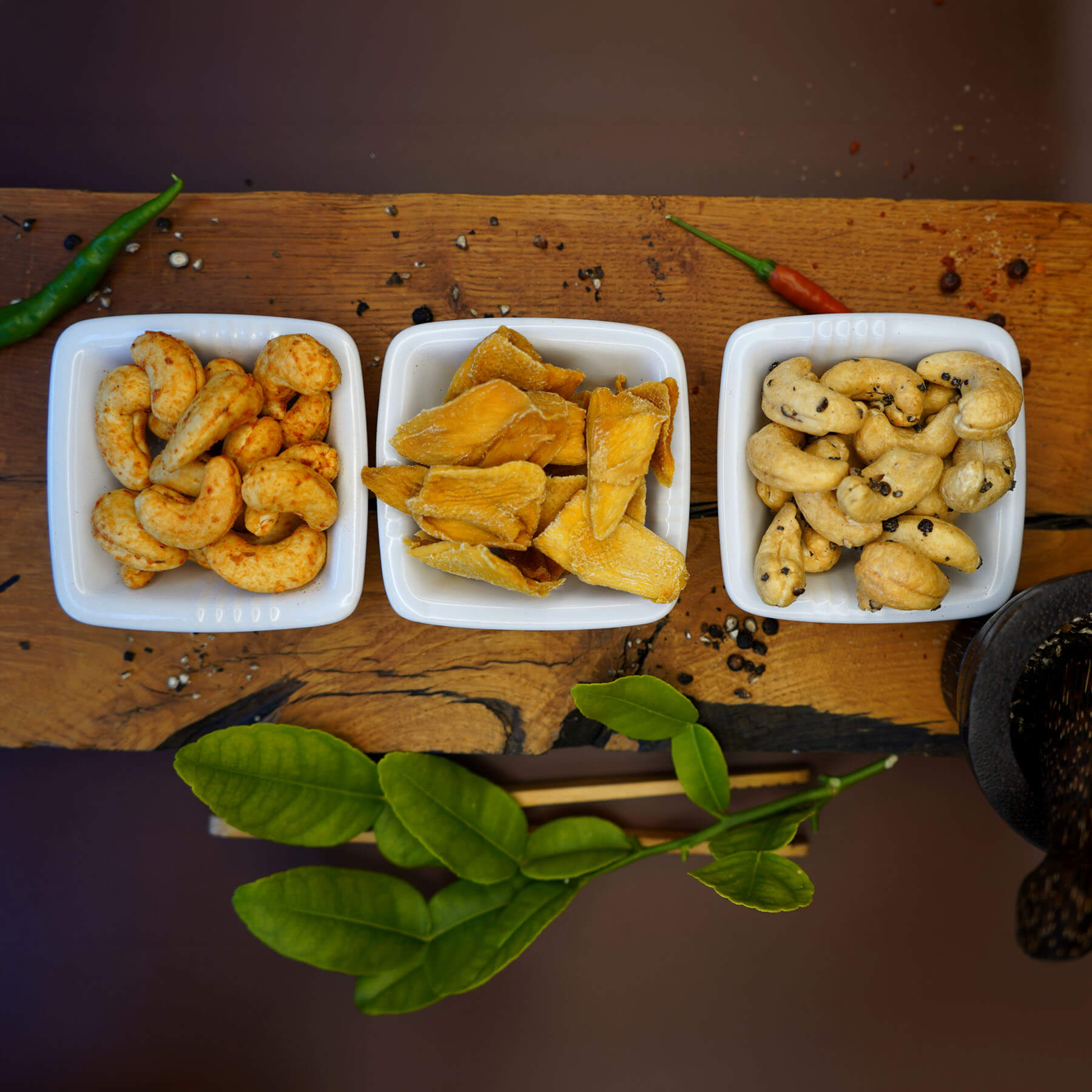 Red-Pepper-Cashews, getrocknete Mango und Black-Pepper-Cashews in drei Schälchen